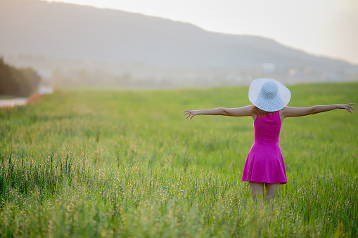 Beautiful young woman standing back countryside, rustick nature place in green field with blue sky copy space.