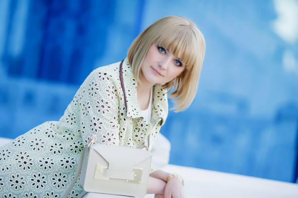 image à la mode d'automne de la jeune femme mignonne avec les poils courts et le sourire candide. manteau tendance, jeans en denim. étudiant femelle posant inver mur jaune. extérieur. - glamour urban scene beautiful one person photos et images de collection