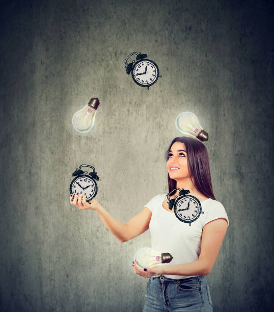 Happy young woman juggling bright lightbulbs and alarm clocks Smart time management concept. Happy young woman juggling bright lightbulbs and alarm clocks time management student stock pictures, royalty-free photos & images