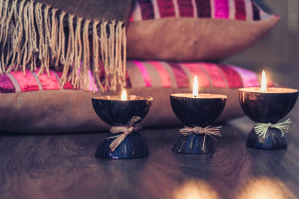 istock Burning spa aroma candles in coconut shell and  burgundy pillows with pattern, cozy home interior background. 1131157500