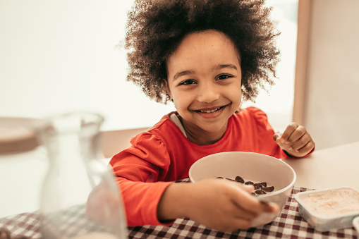 Portrait of cute girl eating cereals for breakfast and smiling.
