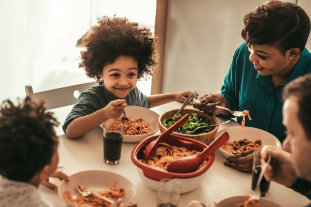 Family Lunch Cute family having lunch together. kids eating noodles stock pictures, royalty-free photos & images