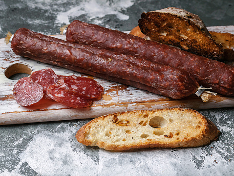 Smoked sausage and ciabatta on a cutting board. Farm natural product. Close-up