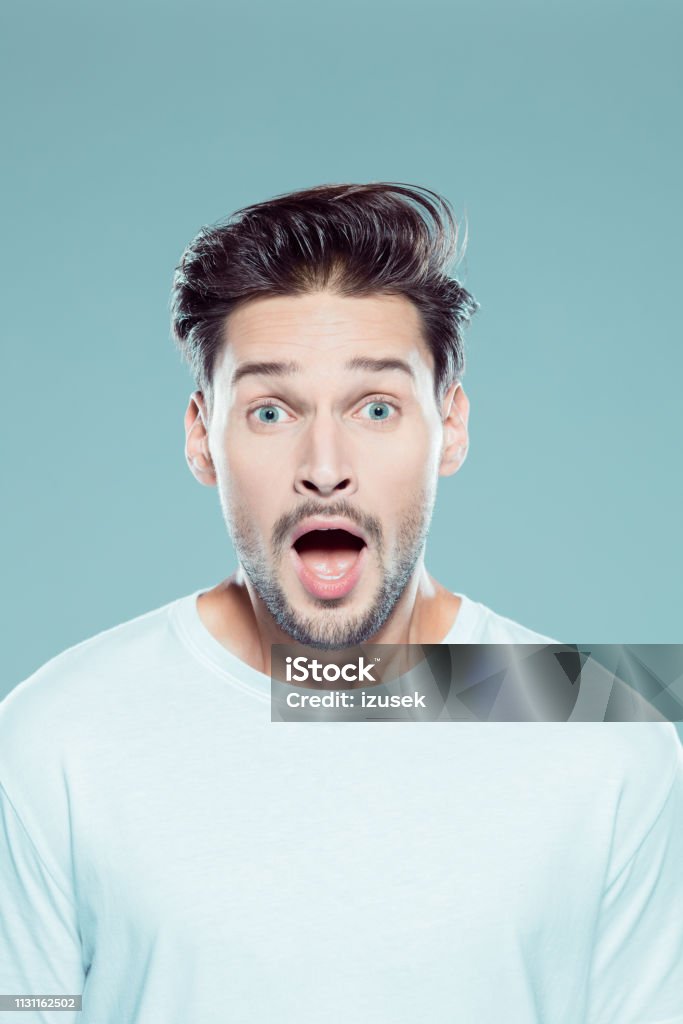 Close up of a surprised young man Close up portrait of surprised young man against gray background Men Stock Photo
