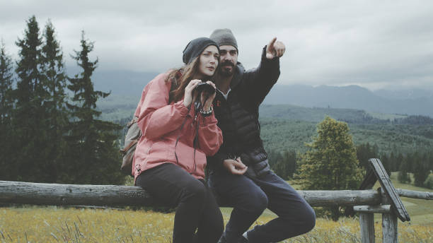 istock Young couple relaxing in the mountains. Using binoculars 1131168329