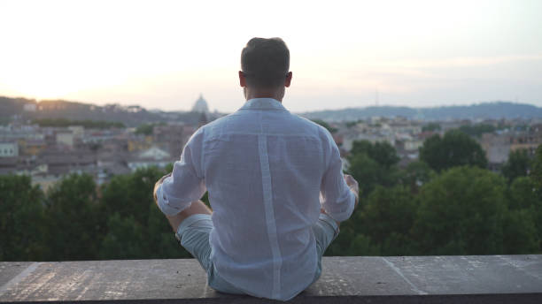 istock Man meditating in lotus pose. Looking at cityscape during sunset 1131168722