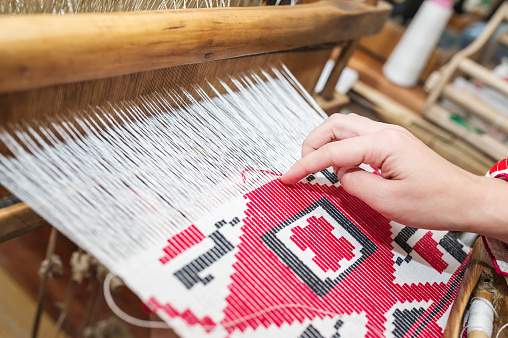 Manos de mujer tejer patrón de color en telar tradicional de madera vintage. photo