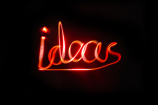 Ideas written with red LED lights with a black background. Light painting with Coloured LED lights used to write the word IDEAS