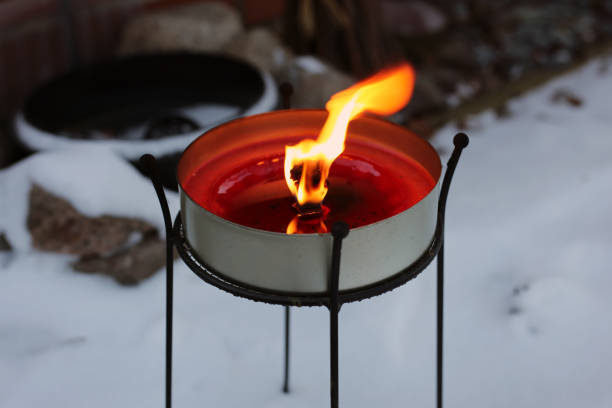 Big red candle burning with a big flame. Photographed outdoors during a cold snowy winter day in Finland. Beautiful home decor element traditionally used during winter including Christmas season.