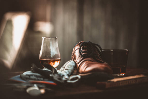 Rustic old workbench with oxford shoe and a glass of whiskey, rough manly tool bench. Picture taken in studio and graded in post to give it a rustic sepia look.