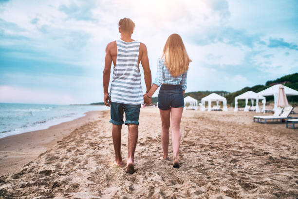 istock Young Couple walking along the beach at sunset 1131190985