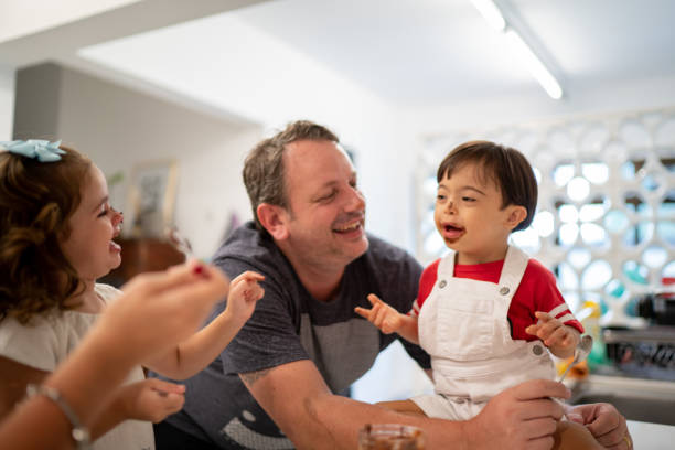 istock Family with twin sibling (Down Syndrome Boy and Girl) having fun eating chocolate 1131194388