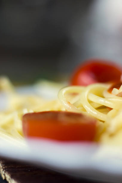 Spaghetti pasta in tomato sauce with cheese and parsley, macro. Italian spaghetti pasta over dark stone background.