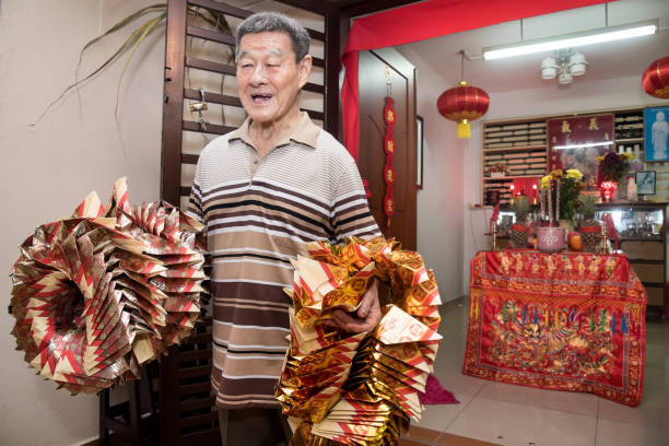 Pai Ti Kong is celebrated on the 8th day of the first month of Lunar calendar. It is a festival of particular significant to Hokkien people (subgroup of Chinese) because it is the birthday of the Jade Emperor who protected the Hokkien people from being massacred.
On this night, the Hokkiens set up a table draped in a red tablecloth with variety of food which are to serve to the Jade Emperor. Some of the most popular items they must have are sweet cakes red tortoise buns, prosperity cakes and bright pink miniature pagodas. Stickers with Chinese characters like “prosperity” and “happiness” were sticked on the fruits and food to resemble good wealth, luck, health for the family in the whole year.
Also particularly relevant are the piles of gold paper folded into the old-style shape of money. These papers are hung from the sugarcanes before being burnt as a thanksgiving offering to the Thien Kong. After these gold papers are set ablaze, the family members then took the stalks of sugarcane from the altars nd threw them into the flames. hombre adulto mayor se sintió tan feliz después de hacer sus deseos y llevar montones de papel de oro doblado en la forma de viejo estilo de dinero para quemado como acción de gracias ofrenda al emperador de jade en la octava noche del año nuevo chino.