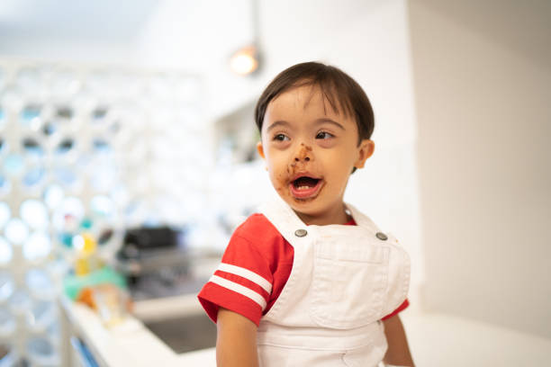 Happy Down Syndrome Little Boy with Chocolate Face at Home