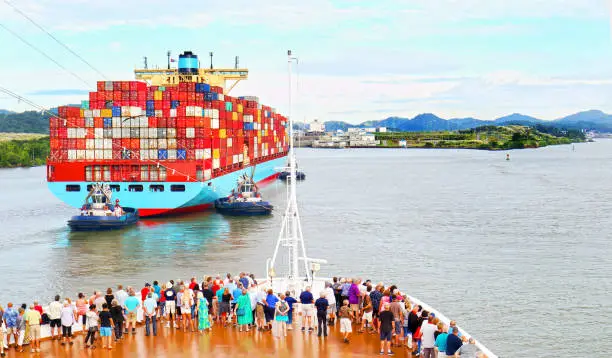 Photo of Cargo Container Ship entering the Panama Canal. Watched by Ship Passengers on Cruiseship Deck