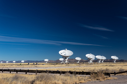 Very Large Array bright white radio antenna dishes against a deep blue sky, New Mexico desert in winter, horizontal aspect