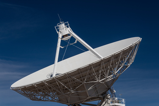 Very Large Array close view of a radio antenna dish against a deep blue sky, space technology, horizontal aspect