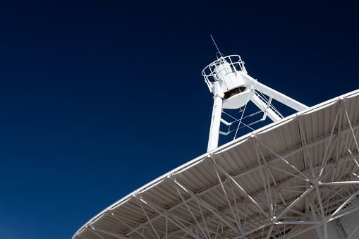 Very Large Array radio telescope pointing into space, white dish against a deep blue sky, space technology, horizontal aspect