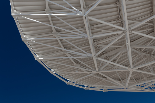 Very Large Array view from bottom of a radio satellite dish at the VLA against a deep blue sky, horizontal aspect