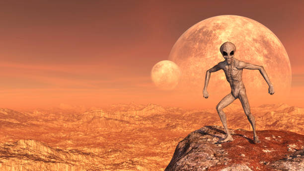 istock Illustration of a gray alien in a combative comical pose atop a mountain peak with moons in the background on a red world. 1131203513