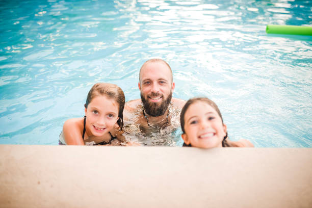 istock Fun in the pool, father and two daughters 1131203580