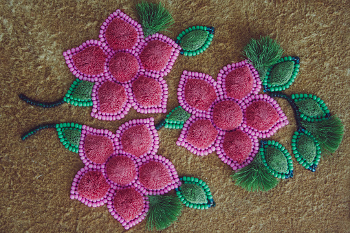 Pink beaded flowers and moose hair tufting on leather with green leaves