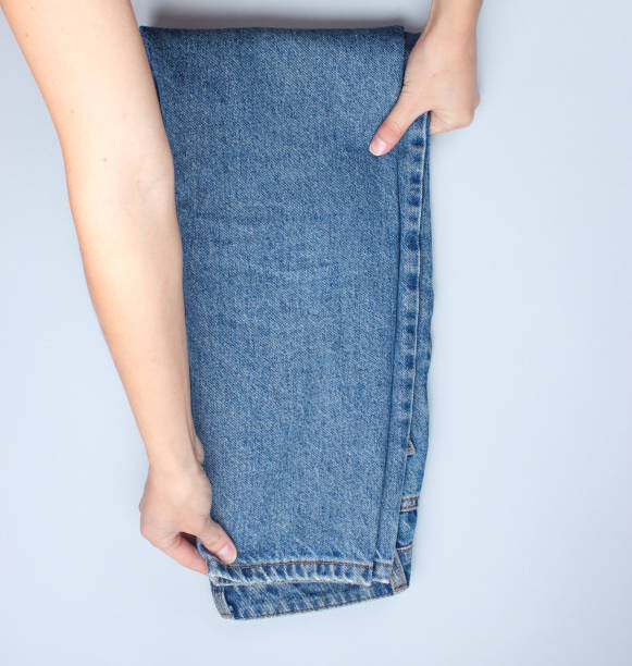 istock Hands fold jeans on a gray background. Conceptual photo. Top view 1131203751