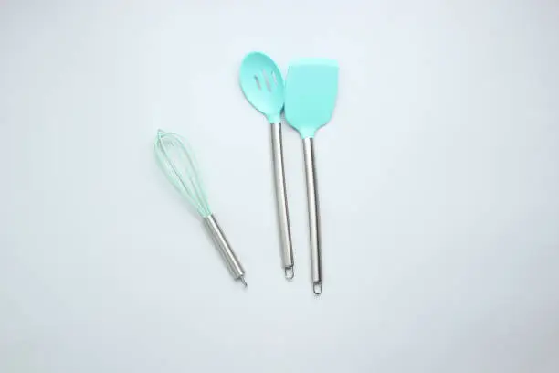Silicone spatulas for cooking, ladle, whisk with a metal handle on a gray background. Top view.