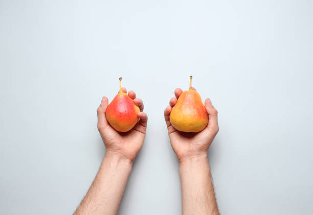 istock Hands holding ripe autumn pears on a gray background. Top view. Minimalism 1131205804