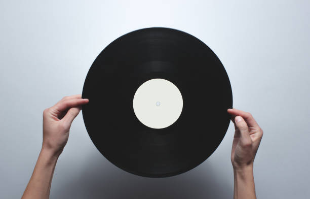 istock Female hands holding a retro vinyl record on a gray background. Top view, minimalism. 1131206355