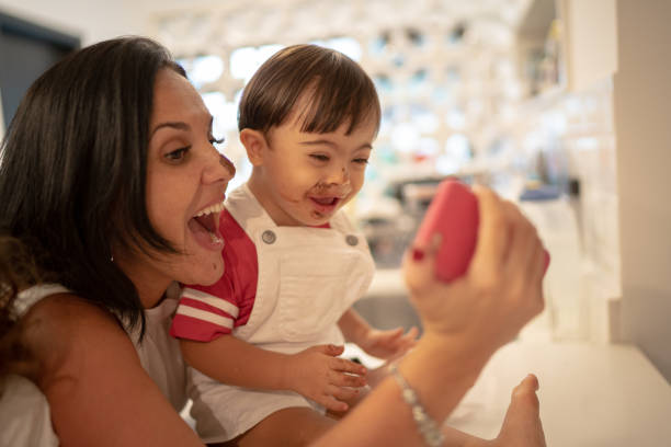 madre y el síndrome de down hijo tomando un selfie después de comer chocolate - playing playful baby contemporary fotografías e imágenes de stock