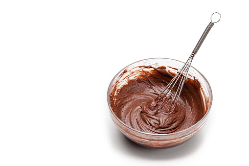 High angle view of a large mixing bowl filled with chocolate dough mix and a wire whisk shot on white background. Predominant colors are brown and white. High key DSRL studio photo taken with Canon EOS 5D Mk II and Canon EF 70-200mm f/2.8L IS II USM Telephoto Zoom Lens