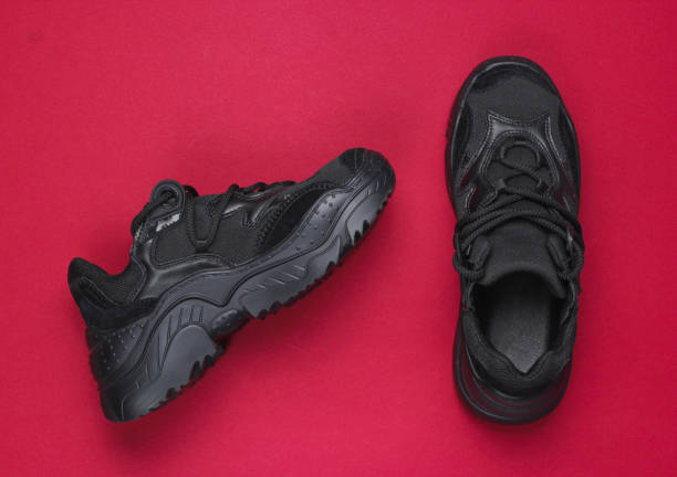 istock Fashionable black sneakers boots on a red background. Top view 1131212705