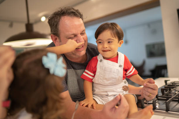 istock Father with Down Syndrome son and daughter having fun eating chocolate 1131213891