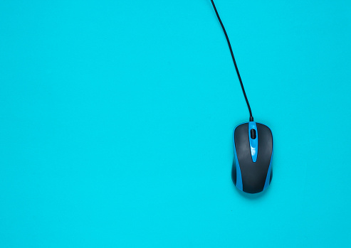 Wired pc mouse on blue background. top view