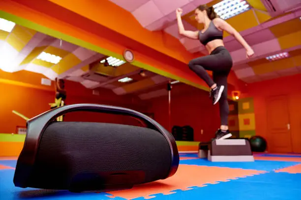 Portable acoustics in the aerobics room on the background of a blurred girl training on a step platform.