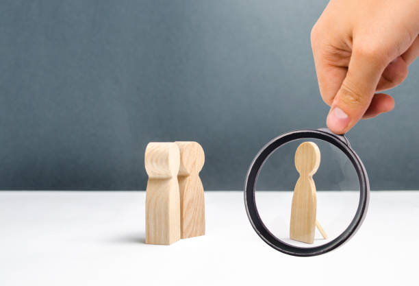 istock Magnifying glass is looking at the false human figure near two human figures looking at it. deception and mosheynik. There are no common interests and topics for communication. Unreal, unreal. 1131218354