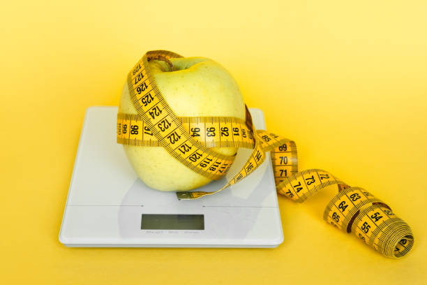red ripe apple and kitchen scale on the white background