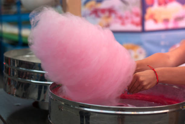 Girl makes pink cotton candy Girl makes pink cotton candy candyfloss stock pictures, royalty-free photos & images