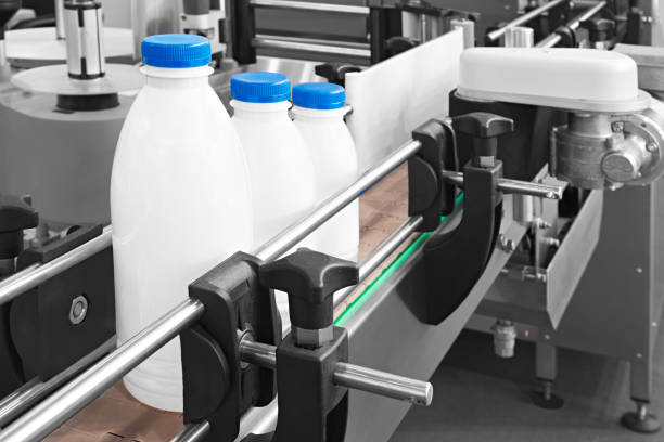 bouteilles en plastique sur la bande transporteuse prête pour verser le lait - milk industry milk bottle factory photos et images de collection