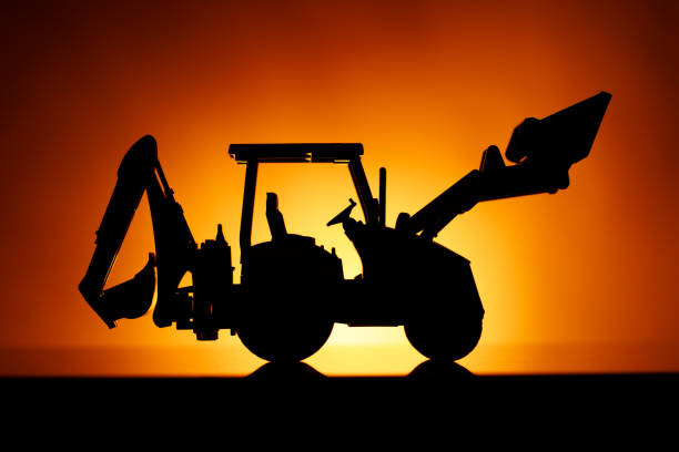 istock backhoe tractor silhouette, orange sunset background 1131235993