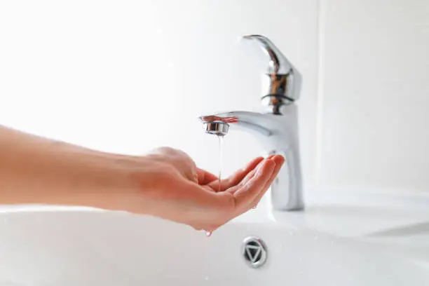 Photo of hand under faucet with low pressure water stream