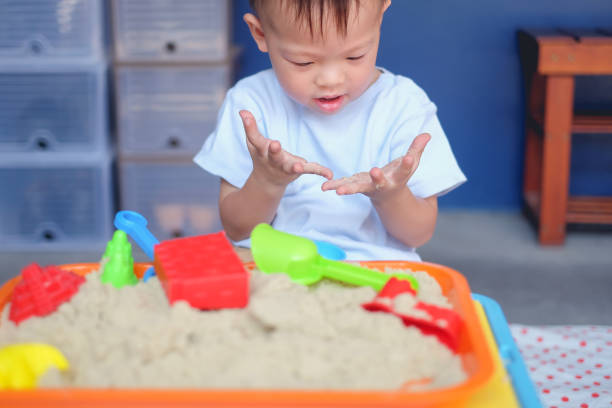 lindo sonriente asiático 2-3 años de edad niño chico jugando con arena cinética en sandbox en casa/guardería/cuidado de día - sandbox child human hand sand fotografías e imágenes de stock