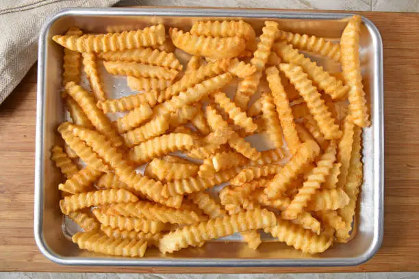 Overhead view of fresh baked crinkle cut french fries in a baking pan