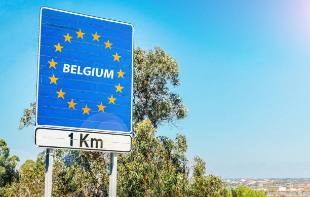 Road sign on the border of Belgium as part of the European Union Road sign on the border of a European Union country, Belgium 1km ahead with blue sky copy space schengen agreement photos stock pictures, royalty-free photos & images