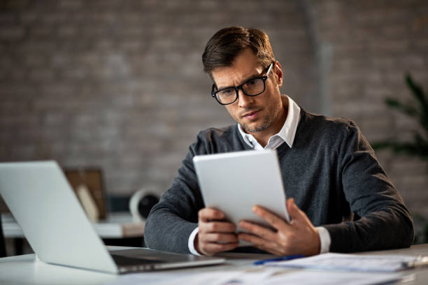 istock Serious businessman reading an e-mail on touchpad in the office. 1131257277