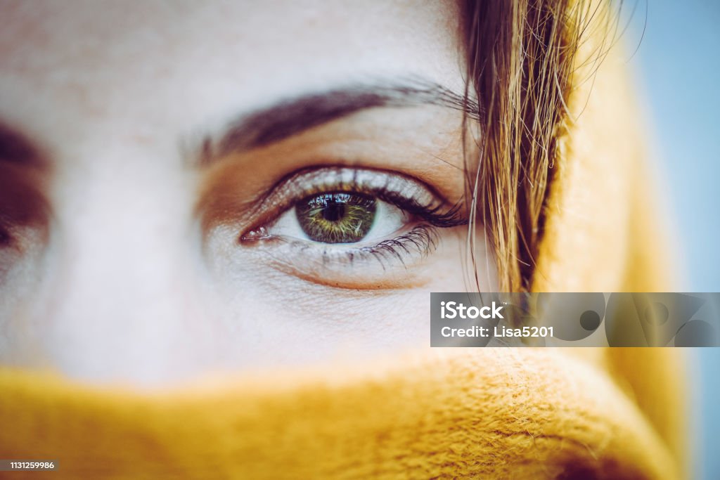 Just the eyes, head covering, young woman Young woman, with striking beautiful eye color wears a bright yellow , millenial yellow ochre scarf around her face and head, close up on only her eyes. Perhaps it is warm weather gear, could also be a burka or religious headscarf. Woman is mysterious, her identity and expression and what she is wearing 30-34 Years Stock Photo