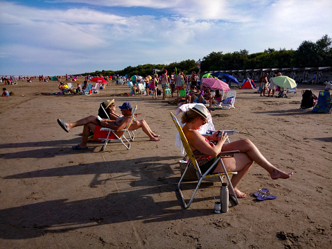 Costa Del Este, Argentina, February 21, 2019:  Tourists enjoy the day  sunbathing on a beach at the Atlantic Ocean.