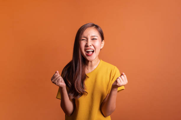 junge asiatische frau porträt über orangefarbenen hintergrund, lächeln glückliche studioaufnahme - smiling single object photography orange stock-fotos und bilder